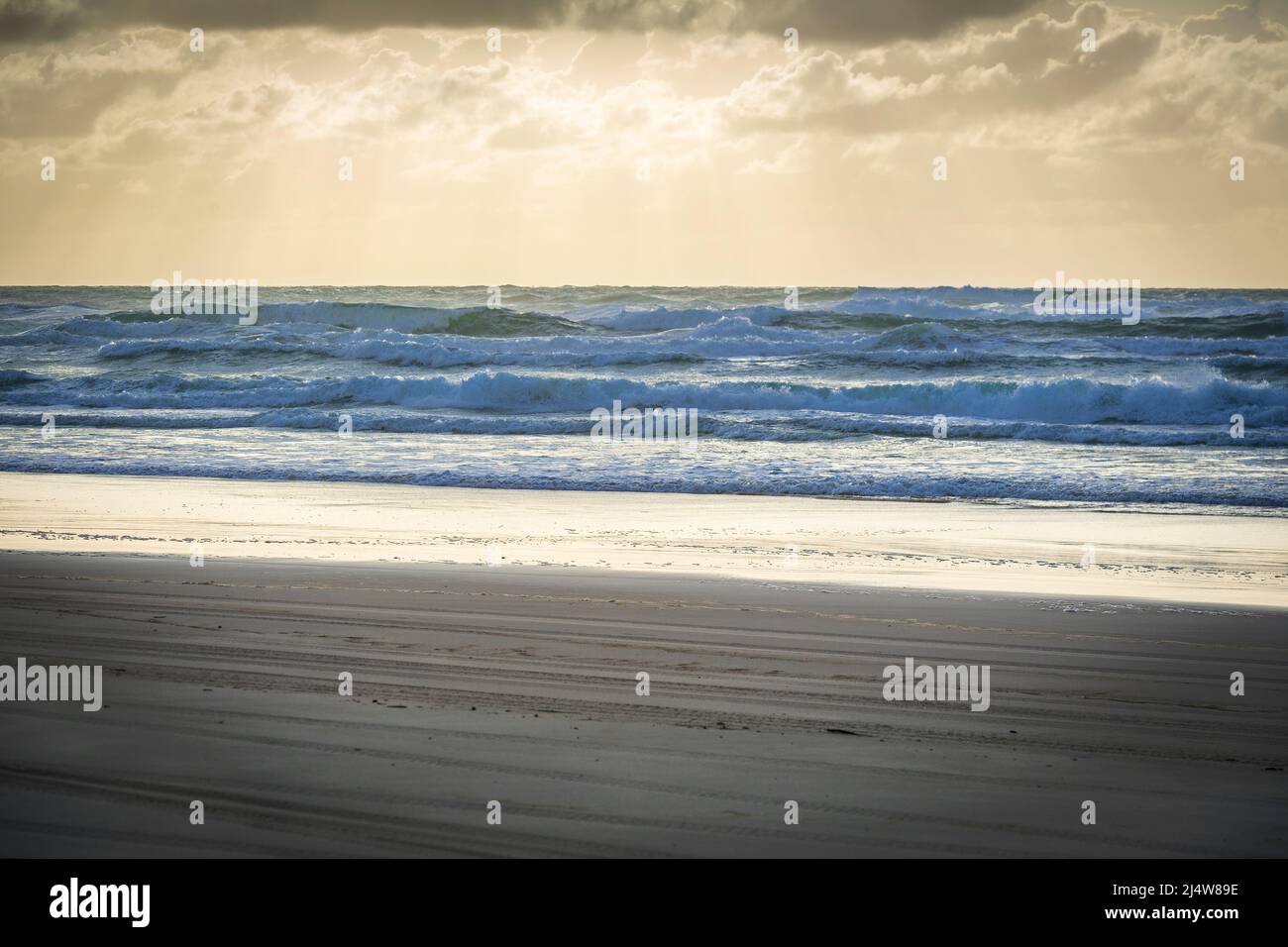 Am frühen Morgen am 75 Mile Beach, mit Lichtstrahlen, die durch die Wolken strömen, was zu einer surrealen Szene führt. Fraser Island, QLD, Australien. Stockfoto