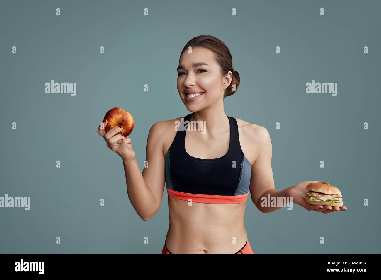 Frau, die zwischen Apfel und Hamburger wählen kann. Diät-Konzept. Stockfoto
