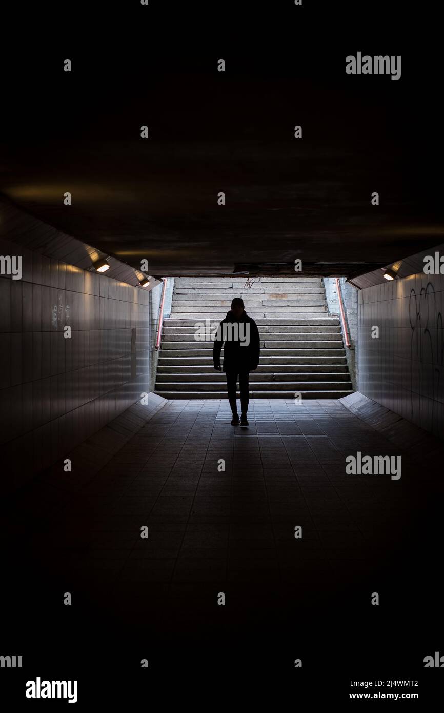 Mann, der in einem dunklen unterirdischen Tunnel läuft. Fremde anonyme Person. Stockfoto