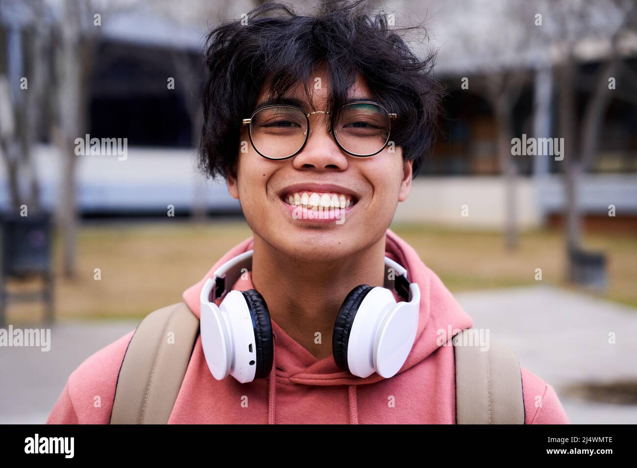 Nahaufnahme eines fröhlichen, glücklichen asiatischen Teenagers, der lächelnd auf die Kamera schaut. Intensives Aussehen eines jungen Mannes. Stockfoto