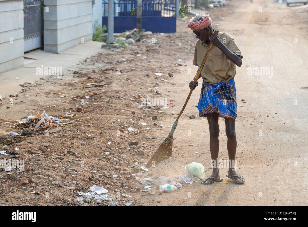Alter Mann, der als Straßenkehrmaschine in Trichy, Tamil Nadu, Indien, arbeitet Stockfoto