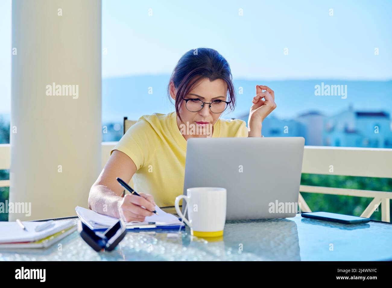 Frau mittleren Alters, die in einem Heimbüro auf einer Terrasse arbeitet. Stockfoto