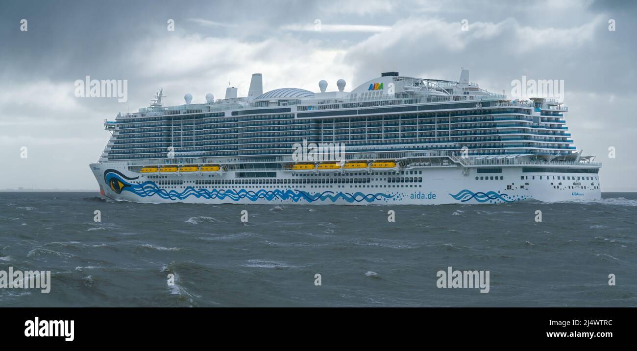 Cuxhaven, Deutschland - 02.25.2022: Enormes Passagierkreuzschiff Aida auf rauem Wasser der Nordsee an einem bewölkten Wintertag. Dramatische Wolken in Th Stockfoto
