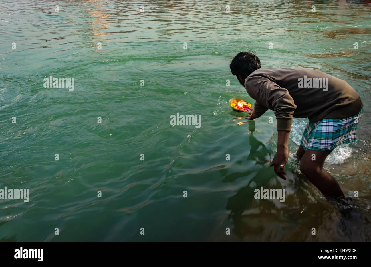 Mann, der Blumentopf zum heiligen Fluss am Morgen aus flachem Winkel Bild anbietet, wird an har KI pauri haridwar uttrakhand indien am 15 2022. März genommen. Stockfoto