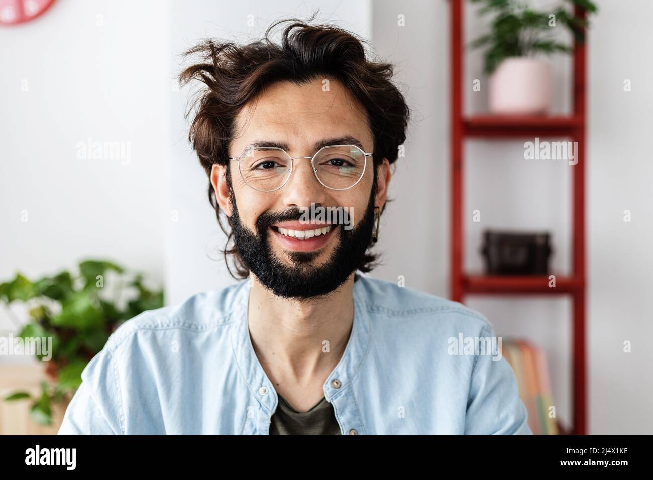Erfolgreicher junger Unternehmer, der bei einem Videoanruf die Kamera anlächelt Stockfoto