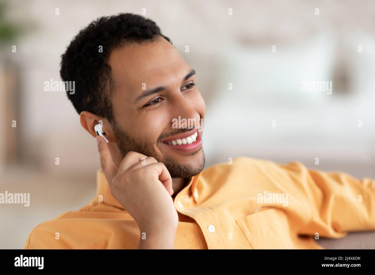 Ruhiger junger Mann, der sich zu Hause ausruhen und Musik hören kann Stockfoto