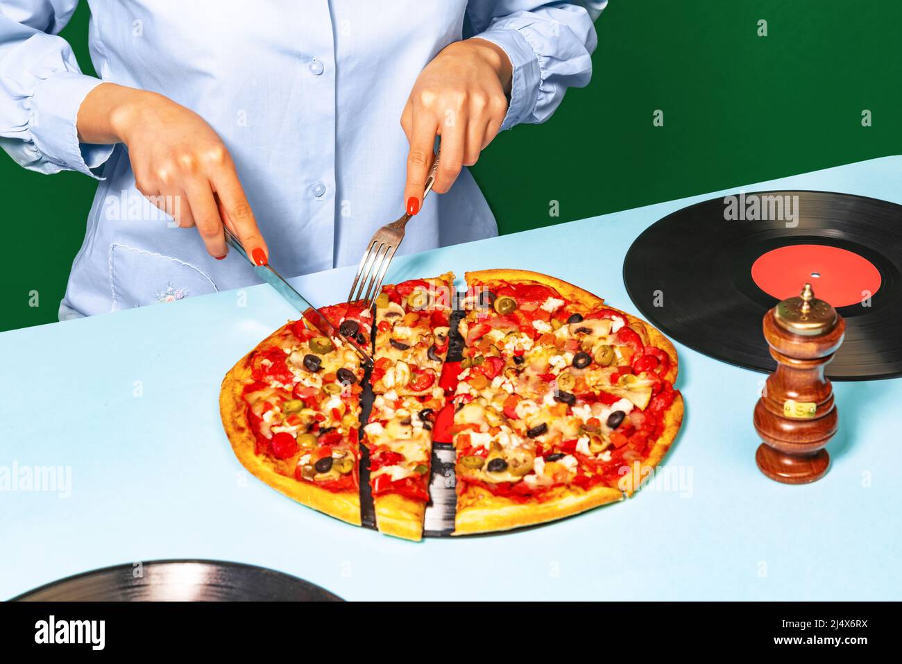 Food Pop Art Fotografie. Weibliche Hände mit italienischer Pizza liegen auf Vinylscheiben auf heller Tischdecke isoliert auf grünem Hintergrund. Vintage-Retro-Style Stockfoto