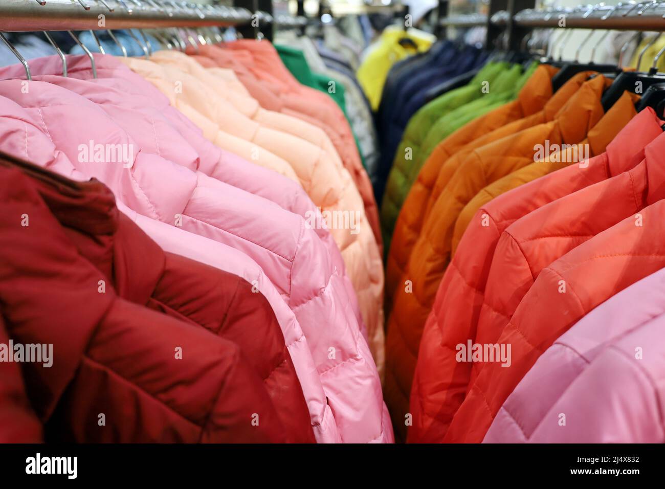 Bunte Damenjacken in einer Reihe auf einem Kleiderbügel im Laden. Neue Frühjahrskollektion Stockfoto