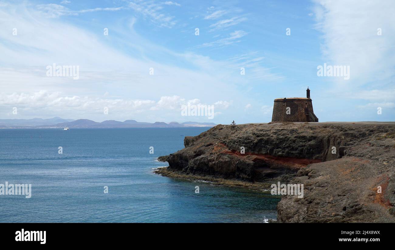 Altes napolionisches Fort auf einer Klippe an der Playa Blanca Lanzarote, Spanien, mit Radfahrern, die bis zum Rand fahren. Stockfoto