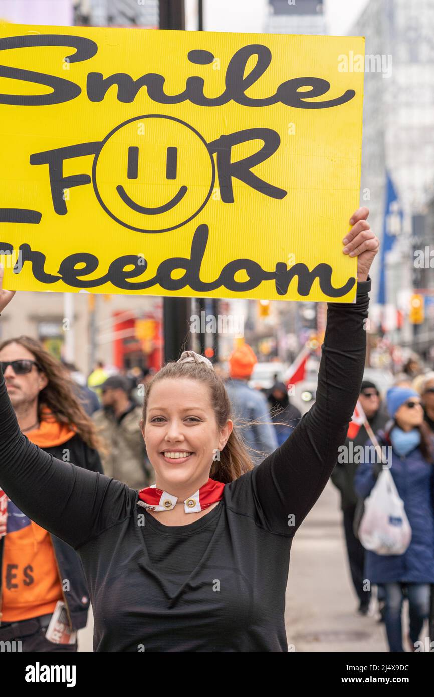 Eine junge Kanadierin hält ein Schild mit der Aufschrift „Smile for Freedom“. Sie ist Teil eines protestmarsches in der Innenstadt (Yonge-Dundas Square District) wh Stockfoto