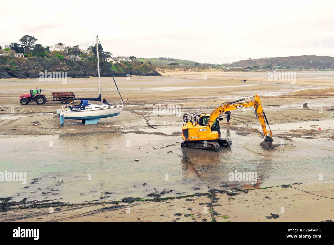Mechanischer Bagger, der Sand verschiebt, um den Navigationskanal bei Ebbe in Abersoch, Llyn Peninsular, Nordwales, zu verbessern Stockfoto
