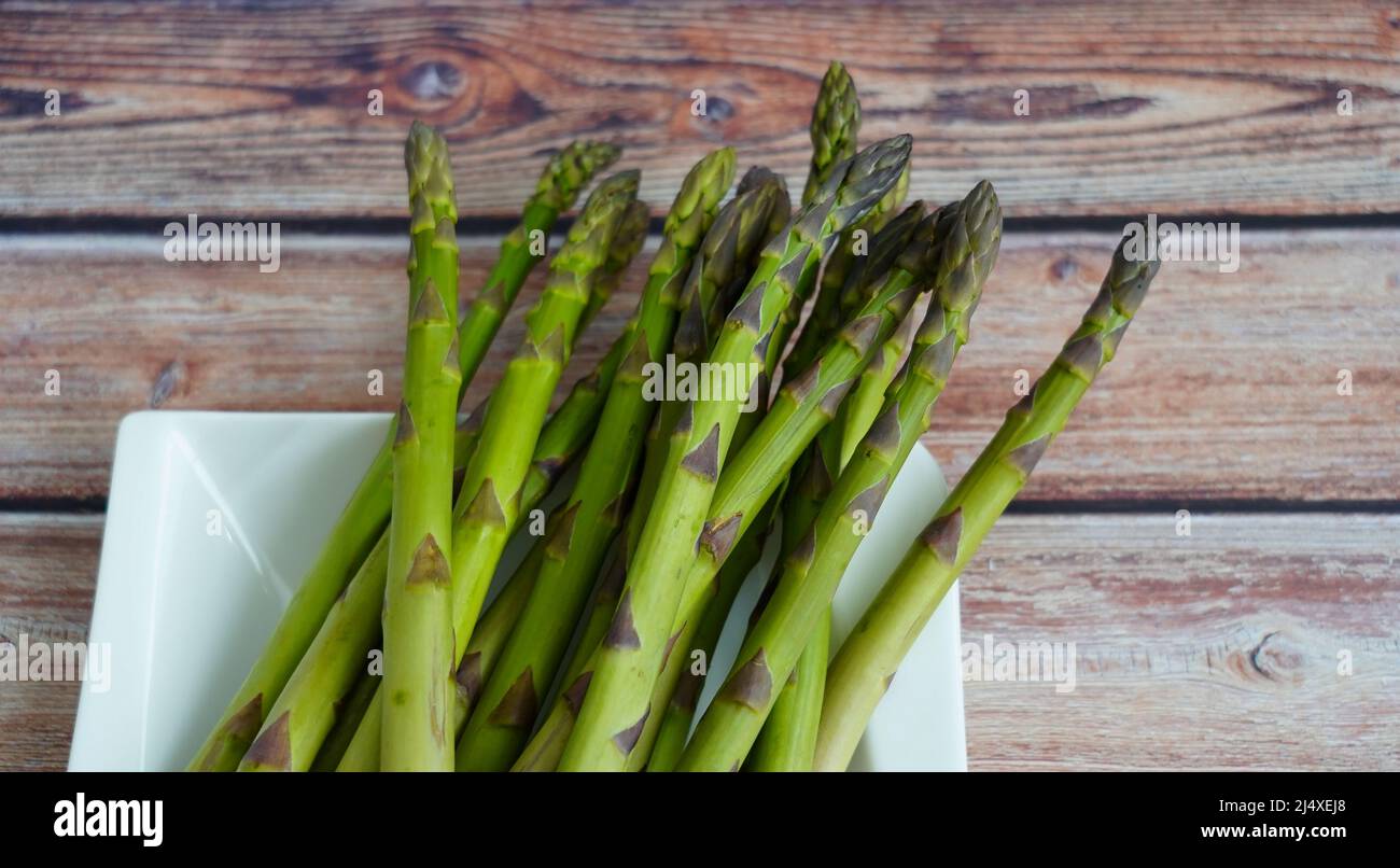 Beschnittene Ansicht von rohem grünem Spargel mit rustikalem Holztisch Hintergrund. Stockfoto