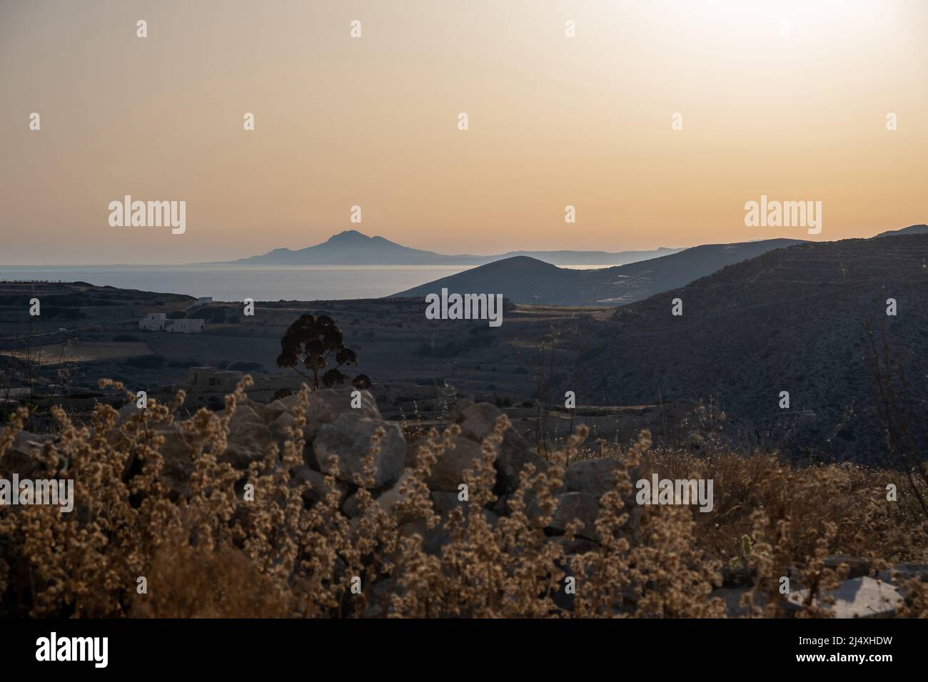 Insel Folegandros, Kykladen, Griechenland. Blick auf das Ägäische Meer von der ländlichen Straße. Gebäude, Natur, Landschaft, blau rosa Nachmittags Himmel Hintergrund. Stockfoto