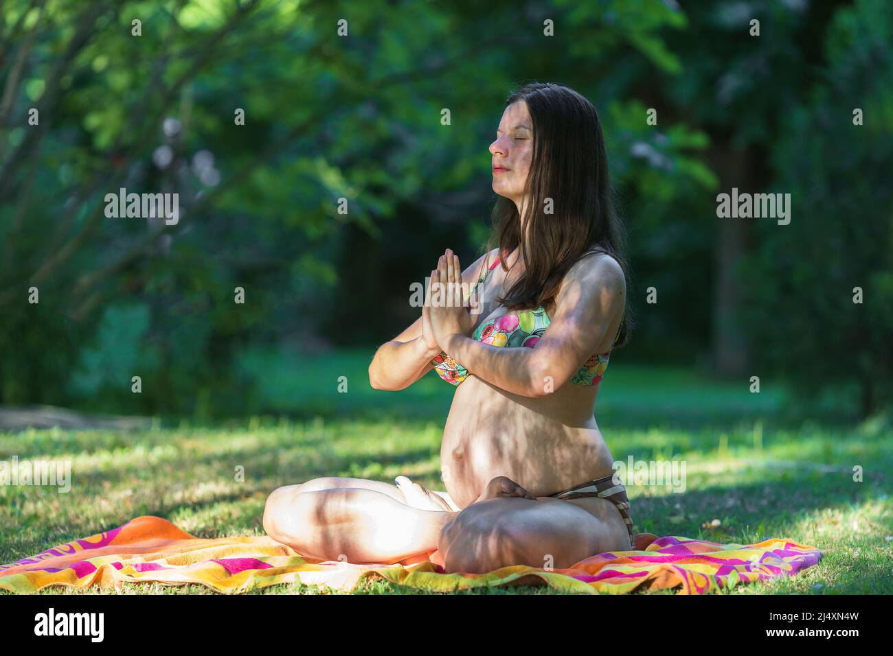 Schwanger junge Frau macht Yoga im Park Stockfoto