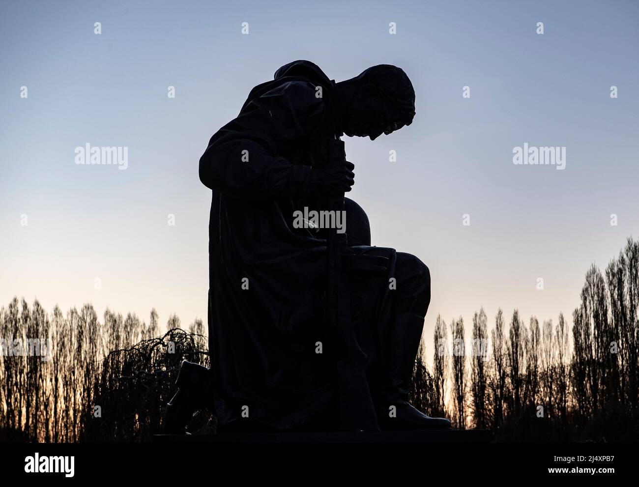 Berlin, Deutschland. 17. April 2022. Die Statue eines knienden Soldaten ist auf dem Gelände des sowjetischen Denkmals im Treptow Park zu sehen. Seit dem russischen Angriff auf die Ukraine gab es immer mehr Inschriften mit politischem Inhalt, die von unbekannten Personen dort platziert wurden. Angesichts dieser Entwicklung hat die Polizei in Absprache mit der Politik Scheinwerfer auf dem Gelände aufgestellt, um im Dunkeln einen besseren Blick zu ermöglichen. Quelle: Paul Zinken/dpa/Alamy Live News Stockfoto