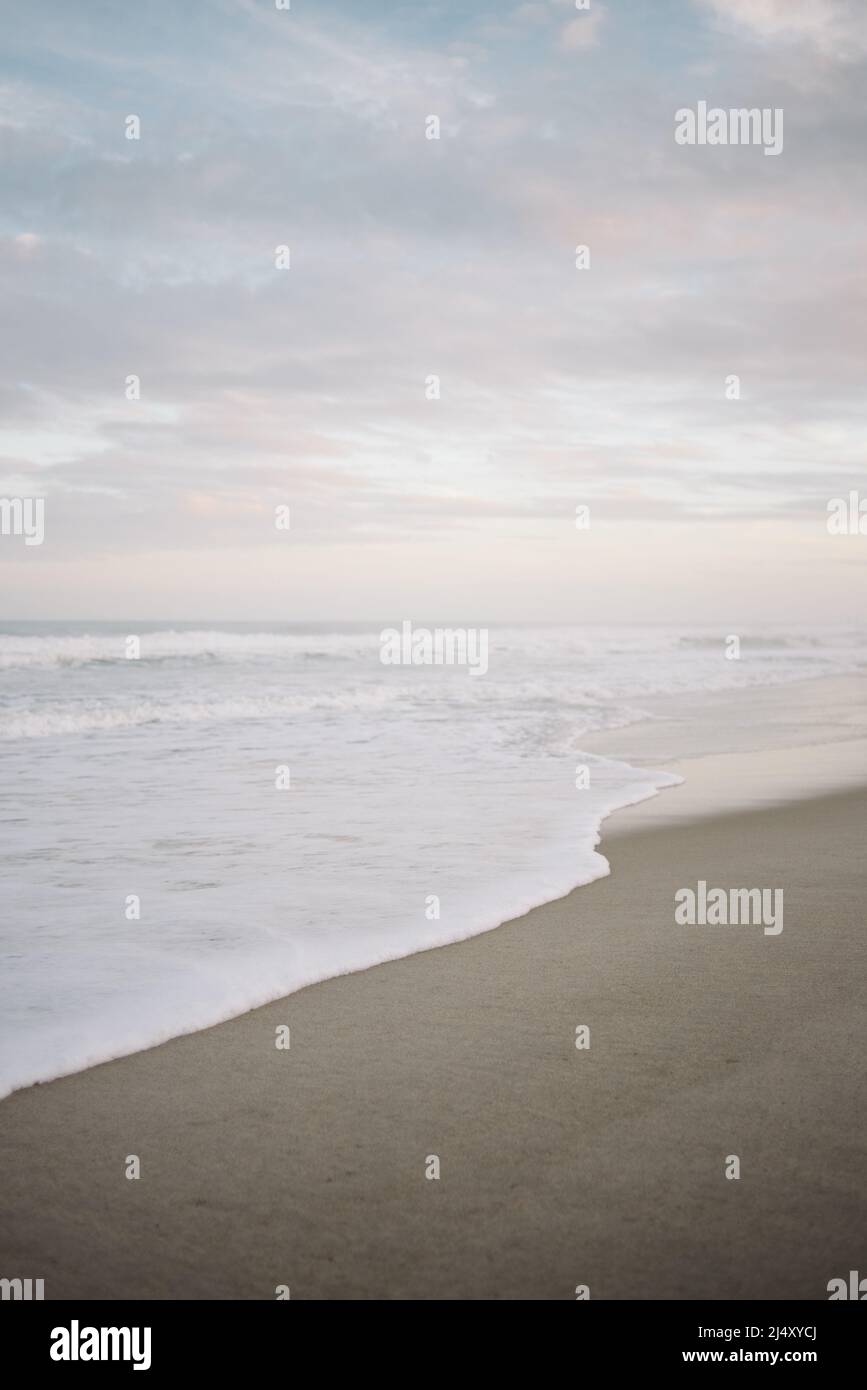 Sanfte Wellen schlagen am Carolina Beach mit rosa und blauem Sonnenuntergang Stockfoto