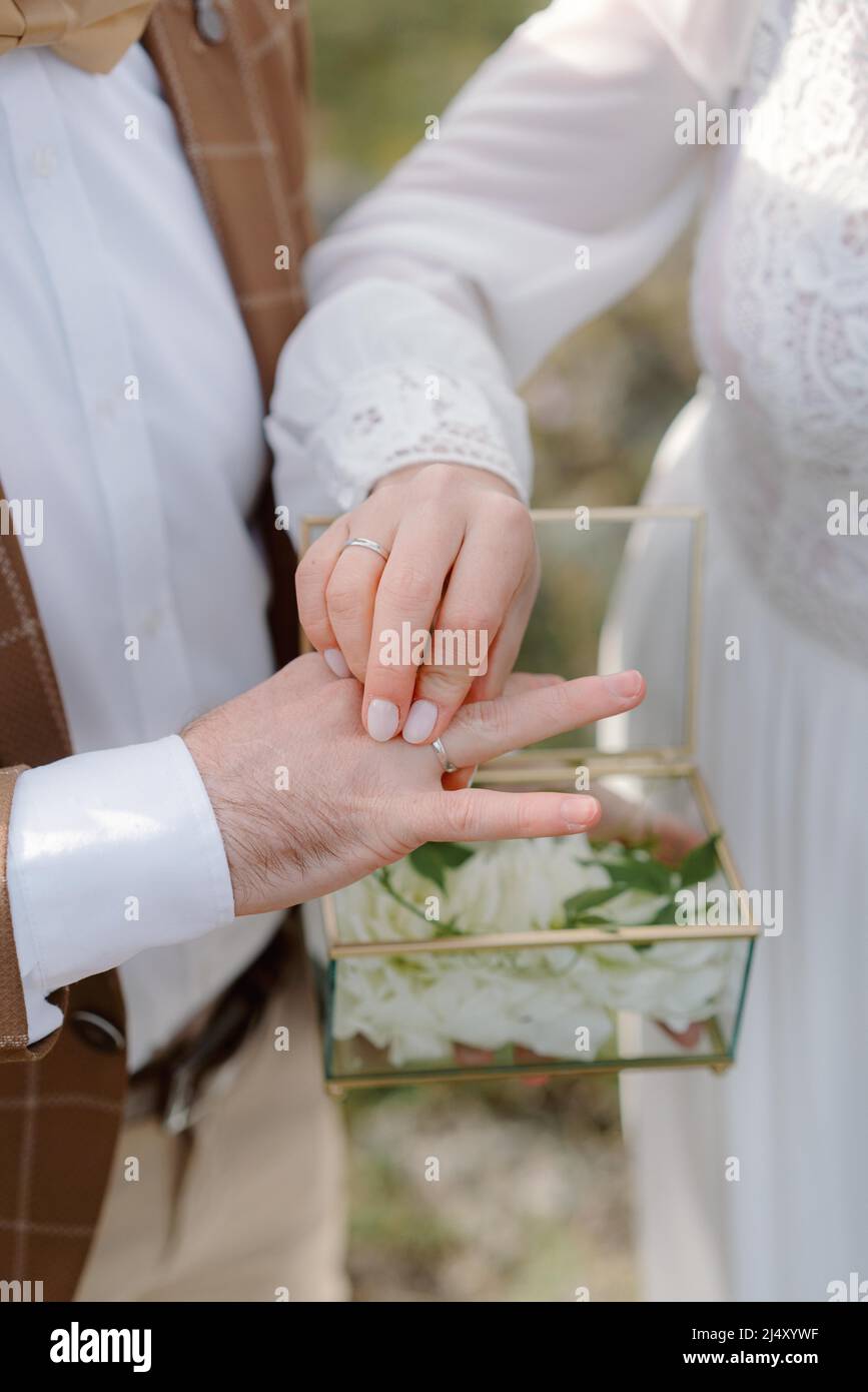 Die Braut legt den Ehering auf den Finger des Bräutigams Stockfoto