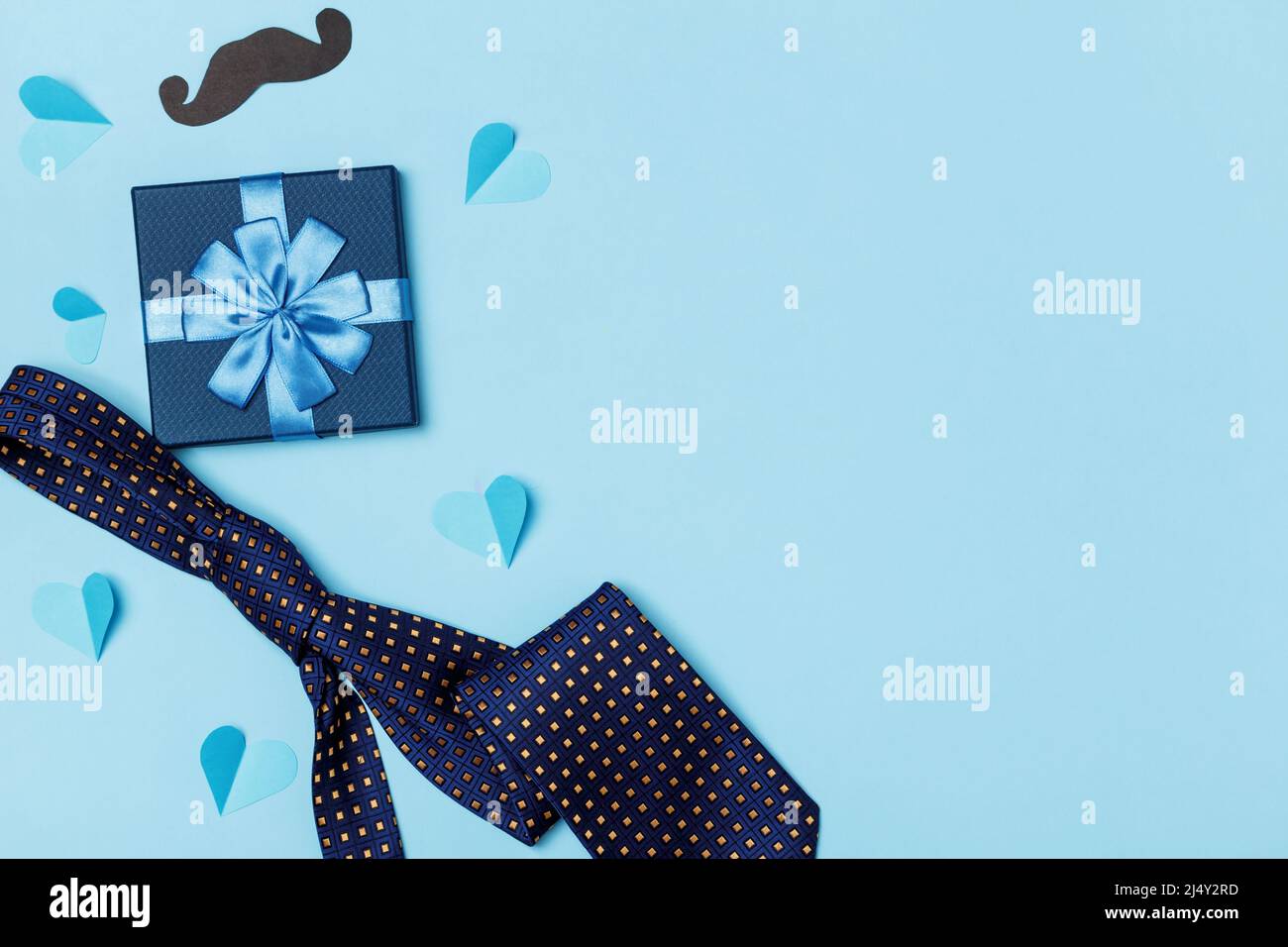 Väter Tag Konzept. Krawatte Schnurrbart Box mit einem Geschenk mit Papier Herzen auf einem blauen Hintergrund. Stockfoto