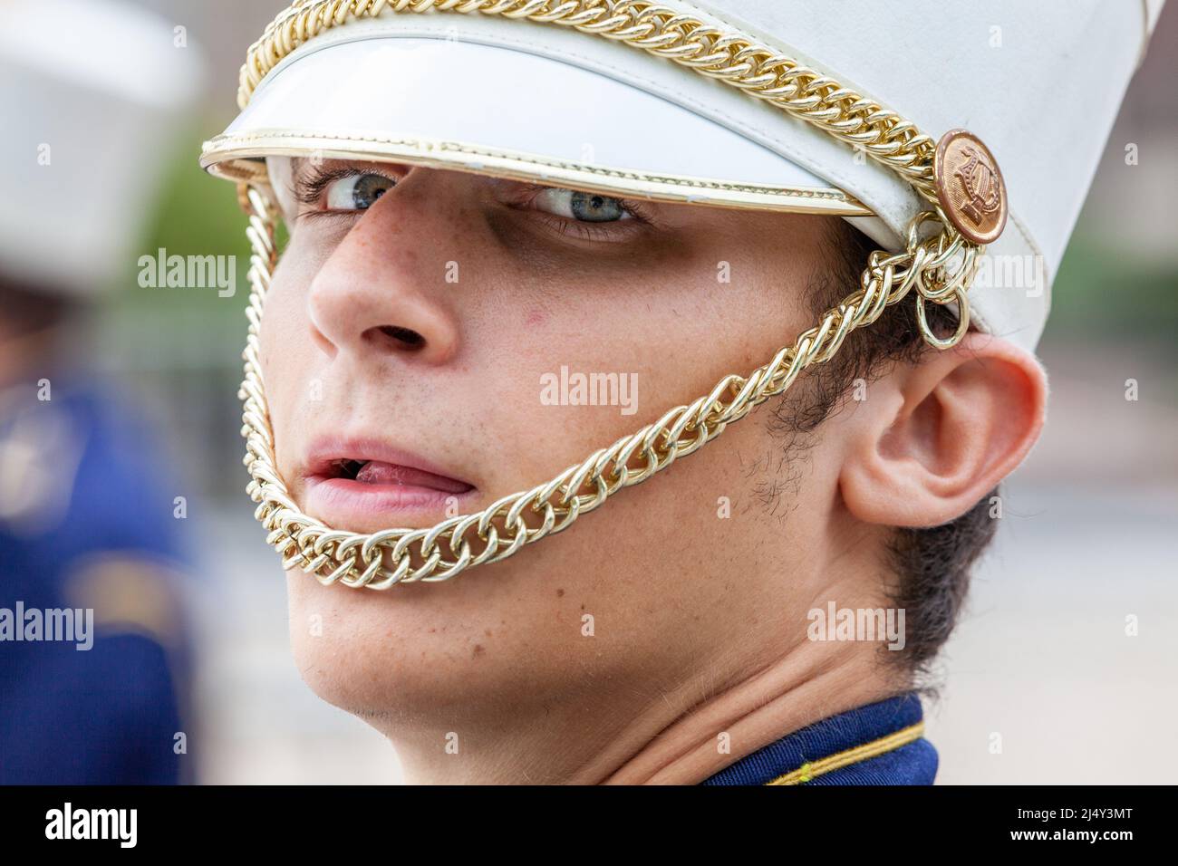 Ein junger Mann, der einen alten Militärhut mit einer Kette trägt und über seine Schulter auf den Fotografen schaut. Brüssel Stockfoto