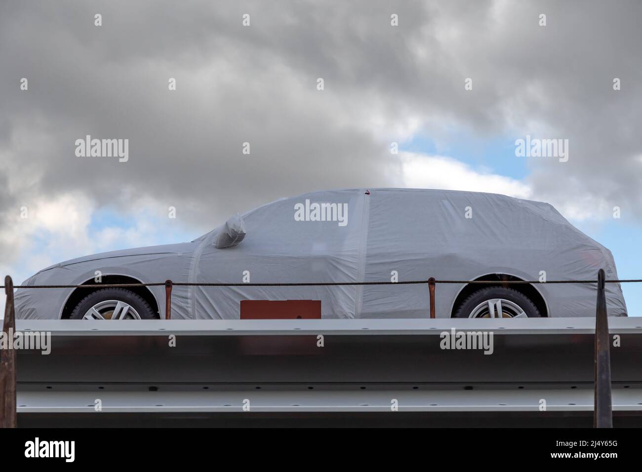 Neues Auto mit weißer Schutzfolie auf Güterwagen Stockfoto