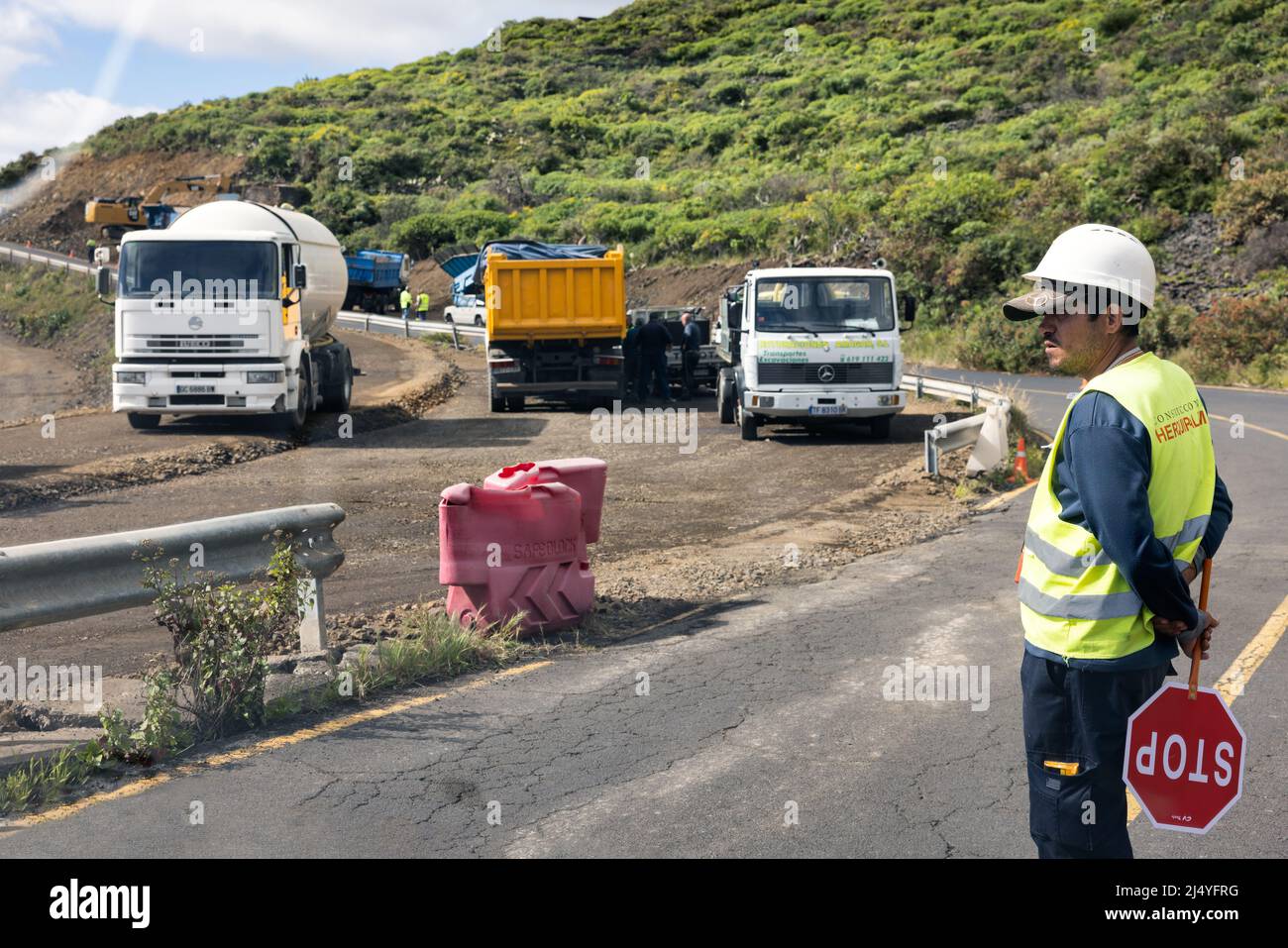La Palma Island Spanien - 08. März 2022: Verkehrskontrolleur bei der Arbeit in der Nähe der Straße Baumaßnahmen mit schweren Geräten und Lastwagen Stockfoto