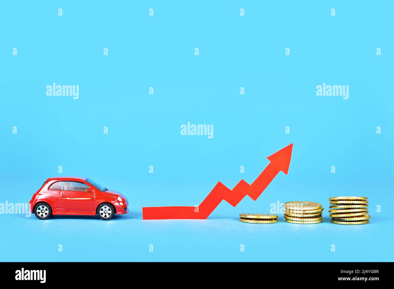 Kleines Auto mit aufsteigendem Pfeil und Geldmünzen auf blauem Hintergrund Stockfoto