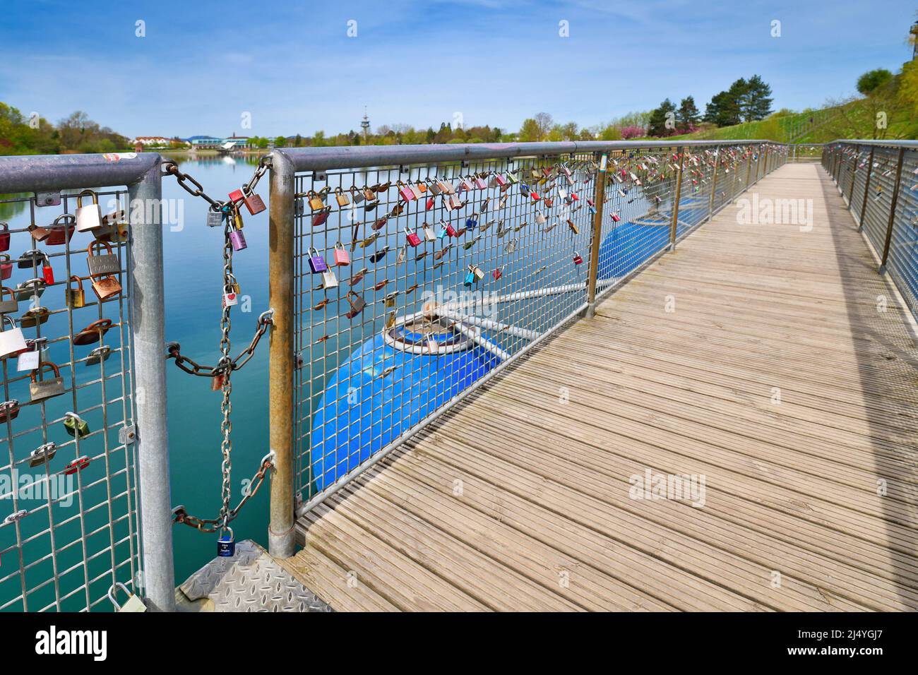 Freiburg, Deutschland - April 2022: Lockenschlösser an Geländer einer schwimmenden Brücke mit blauen runden Schwimmern namens Seeparkbrücke Stockfoto