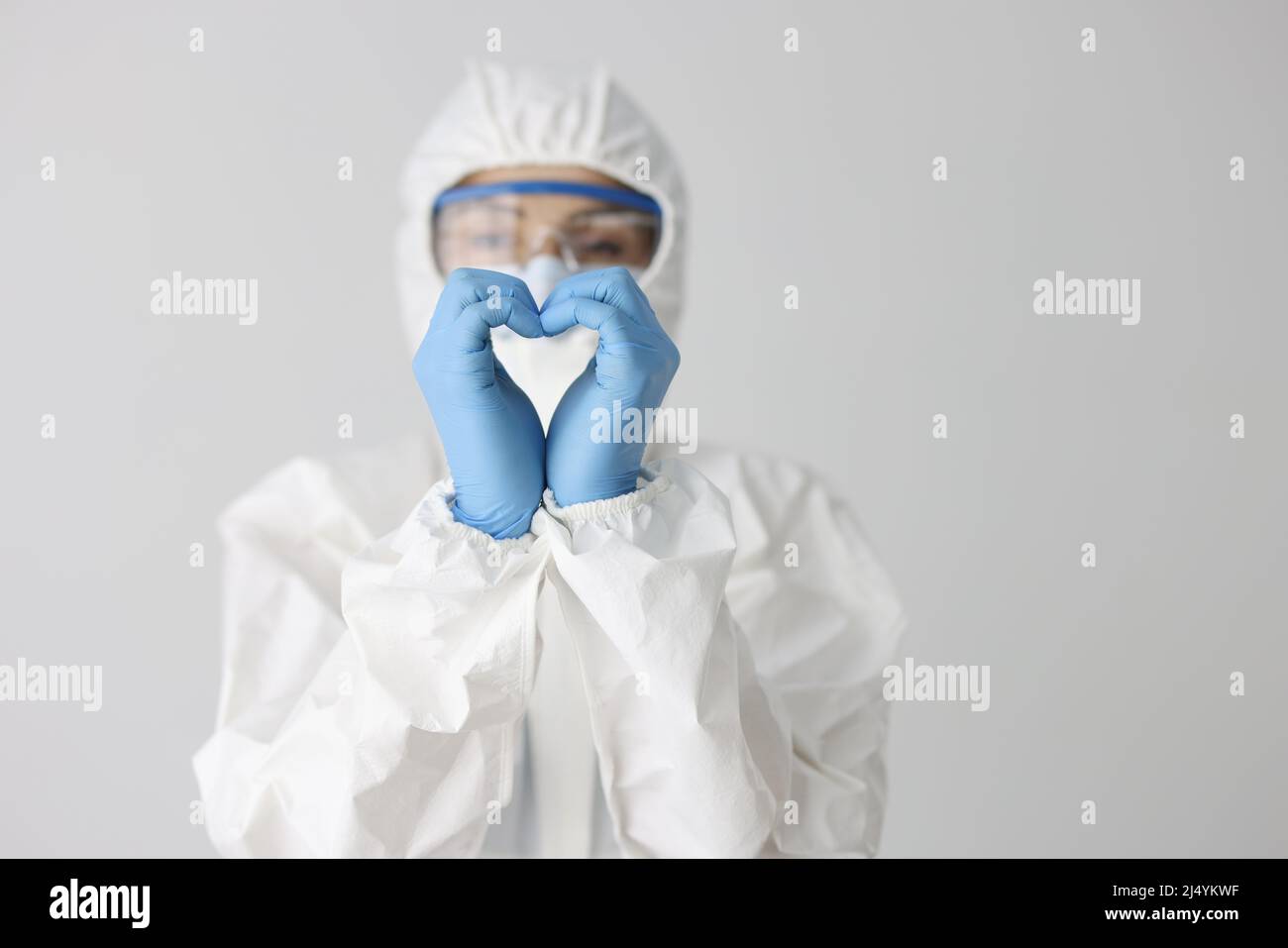 Der Arzt in Schutzanzug macht mit den Händen eine Herzbewegung Stockfoto