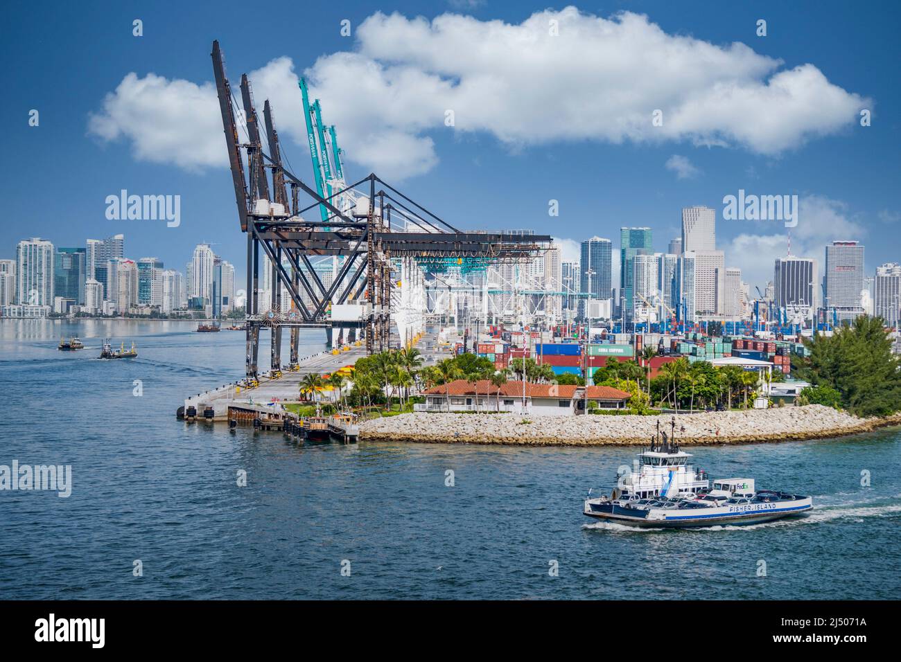 Die Fisher Island Ferry fährt um den Frachtcontainer-Bereich des Hafens von Miami, gesehen vom Deck eines Kreuzfahrtschiffs, das von Miami, Florida, abfährt. Stockfoto