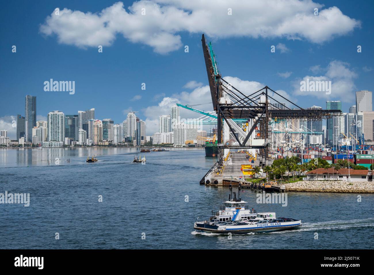 Die Fisher Island Ferry fährt um den Frachtcontainer-Bereich des Hafens von Miami, gesehen vom Deck eines Kreuzfahrtschiffs, das von Miami, Florida, abfährt. Stockfoto