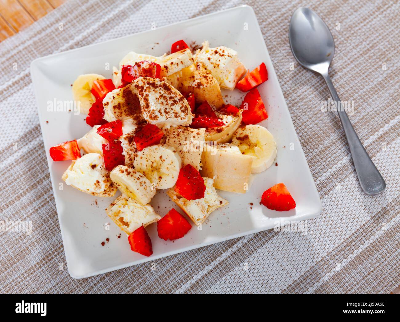 Eis mit gehackten Erdbeeren und Bananen auf dem Tisch serviert Stockfoto