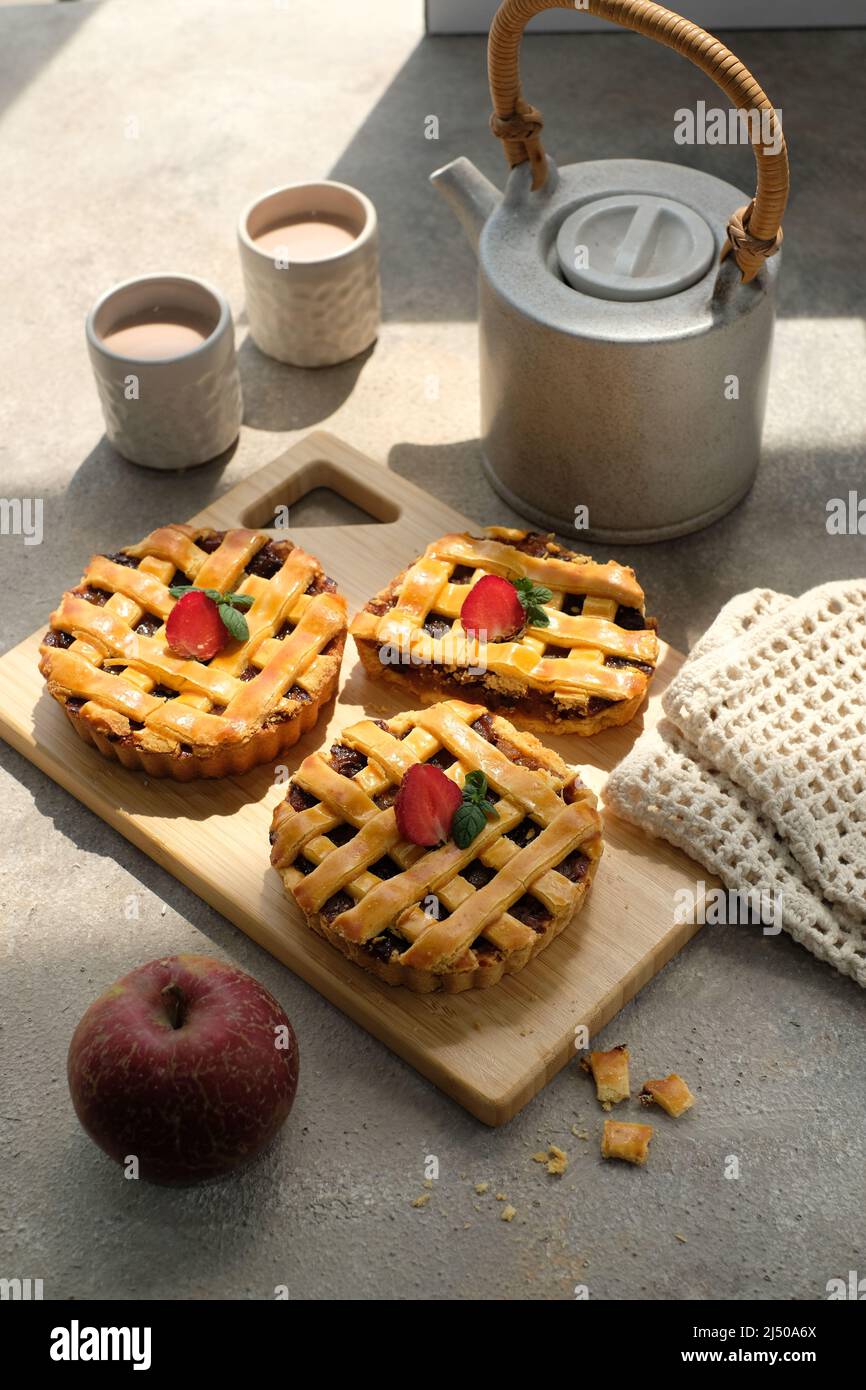 apfelkuchen mit Erdbeerauflage, begleitet von einer Tasse Tee Stockfoto