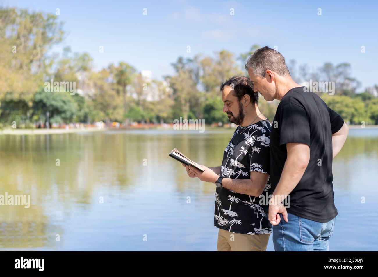 Ein paar reife Männer, die in einem See lesen, mit einer glücklichen und entspannten Haltung Stockfoto