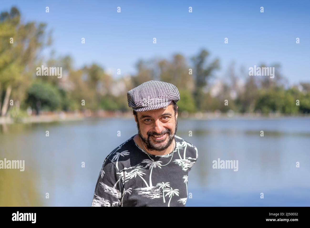 Bärtiger reifer Mann, der an einem See eine Baskenmütze trägt. Speicherplatz kopieren Stockfoto