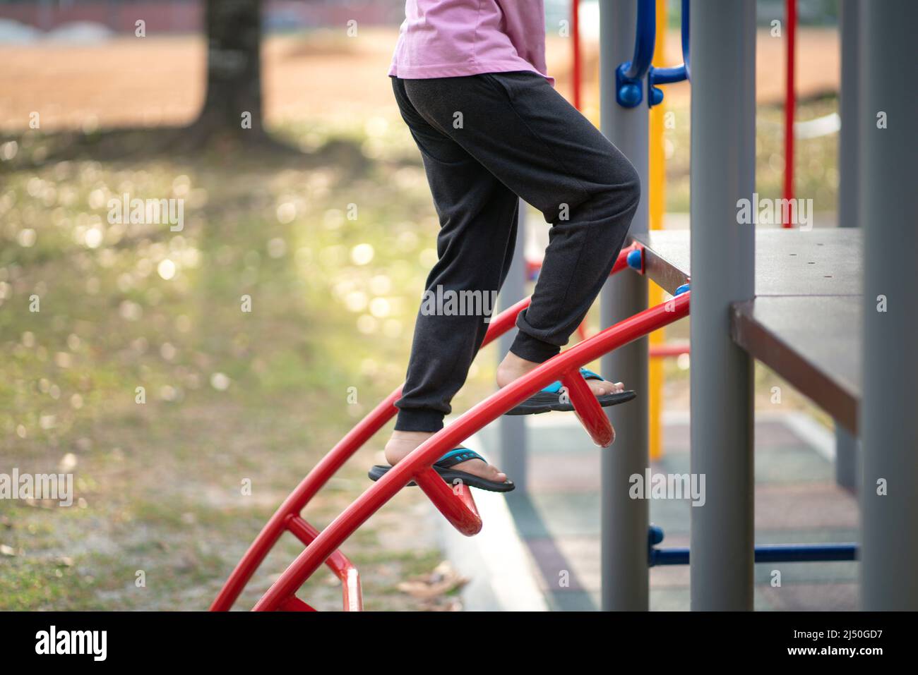 Kind spielt auf einem Kinderspielplatz, im Freien. Nahaufnahme der Beine des Kindes. Stockfoto