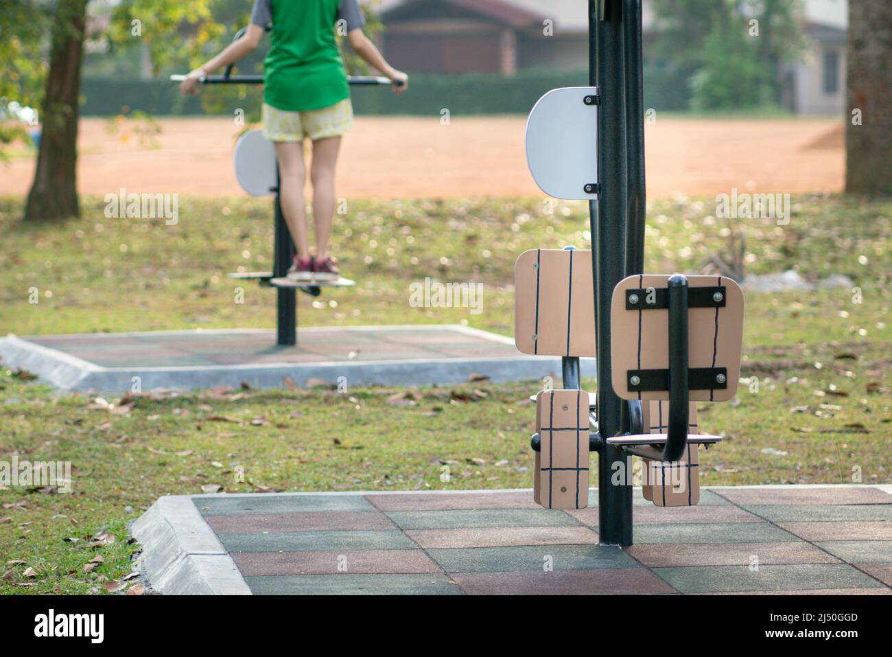 Fitnessgeräte, im Freien, mit einer nicht erkannten Frau, die im Hintergrund trainiert. Sport oder gesundes Lifestyle-Konzept. Stockfoto