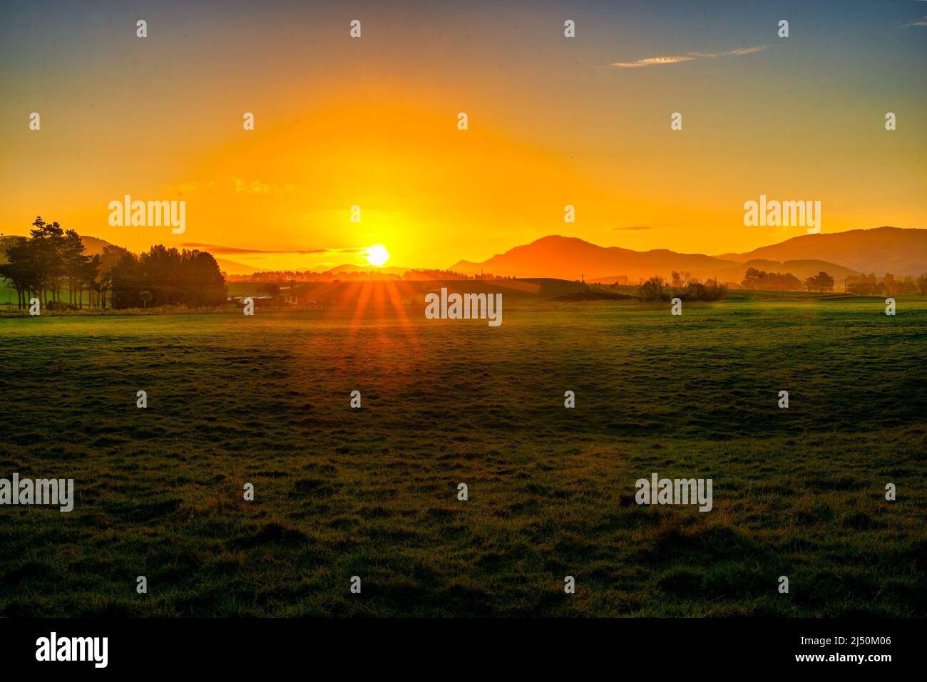 Die Sonne geht über die Hügel und Paddocks in den Catlins unter Stockfoto