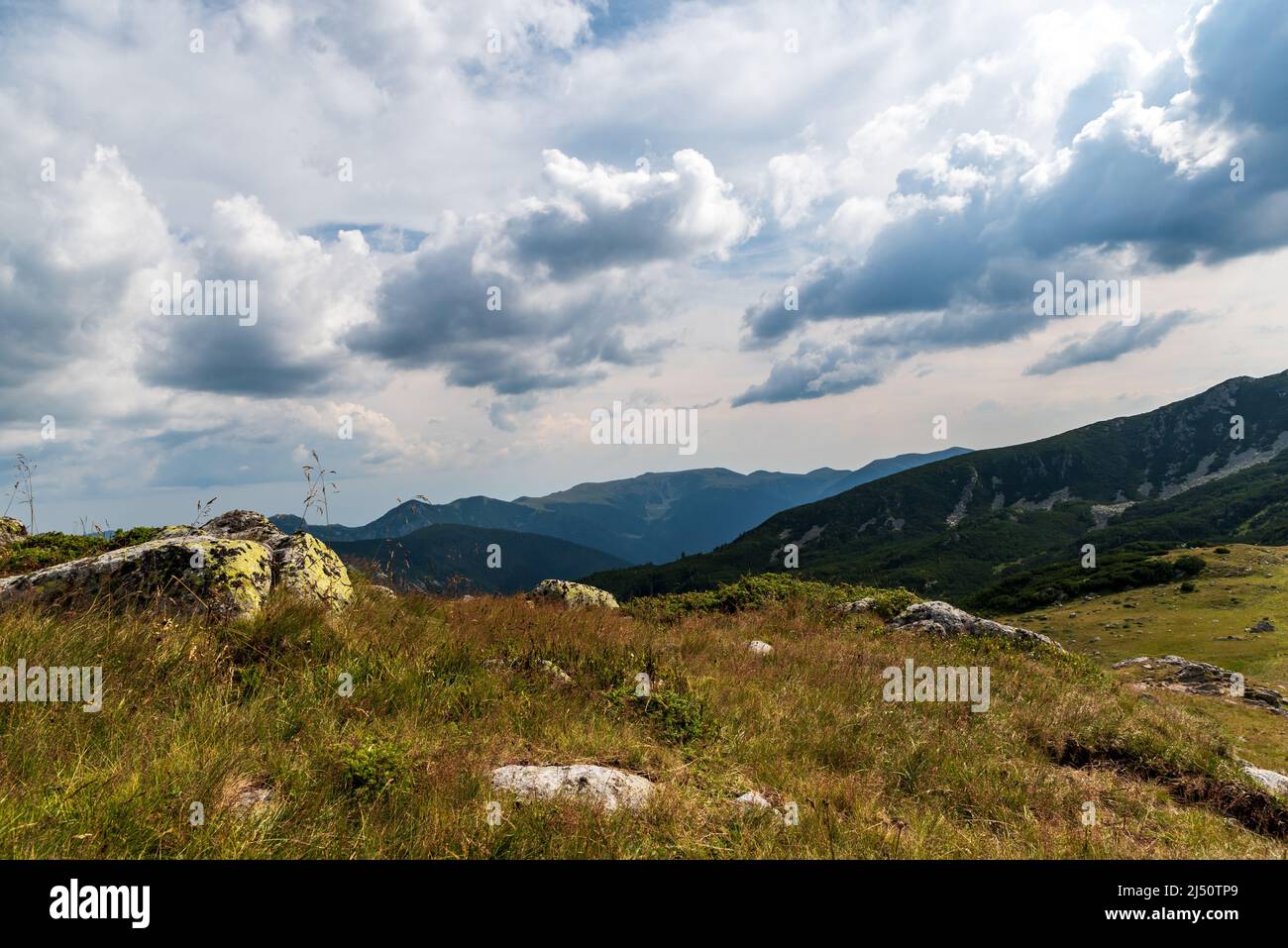Bergkulisse mit Wiese, Steinen und Hügeln im Hintergrund - Blick über den See Zanoaga in den Bergen von Retezat in Rumänien Stockfoto