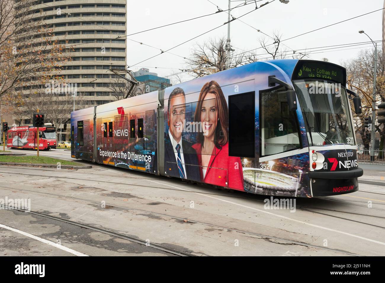 Eine farbenfrohe, moderne Straßenbahn im Zentrum von Melbourne an einem Winters-Nachmittag, die für einen lokalen Fernsehsender wirbt Stockfoto