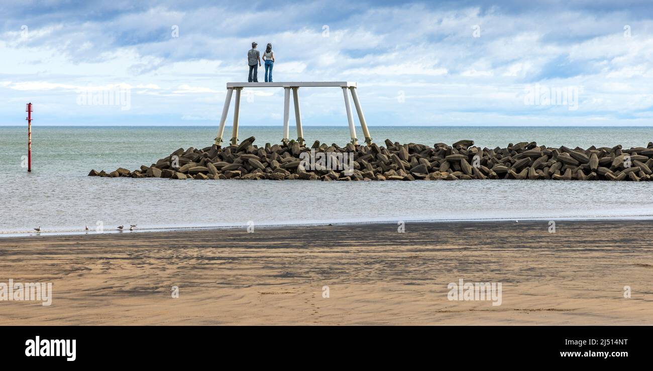 Auf einem Wellenbrecher vor dem Strand in Newbiggin Bay in Northumberland stehend, ist 'The Couple' eine 12,5 Meter hohe Skulptur des Künstlers Sean Henry. Stockfoto