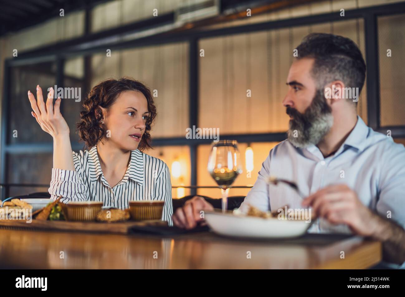 Ein erwachsenes Paar sitzt im Restaurant. Sie unterhalten sich beim Abendessen. Stockfoto