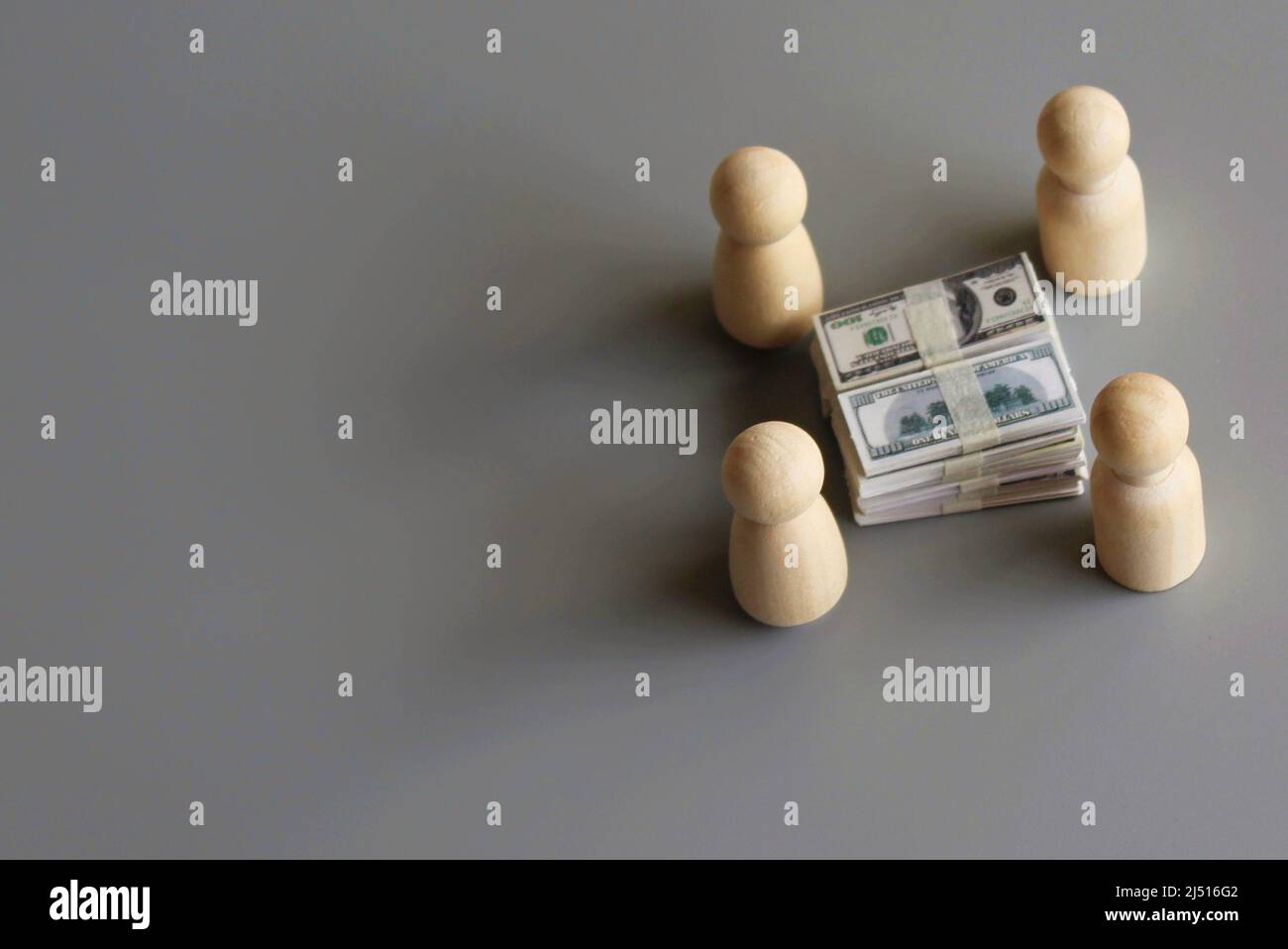 Holzpuppen umgeben einen Stapel Geld. Konzept für Geldbeschaffung, Crowdfunding, Korruptionsprogramme. Stockfoto