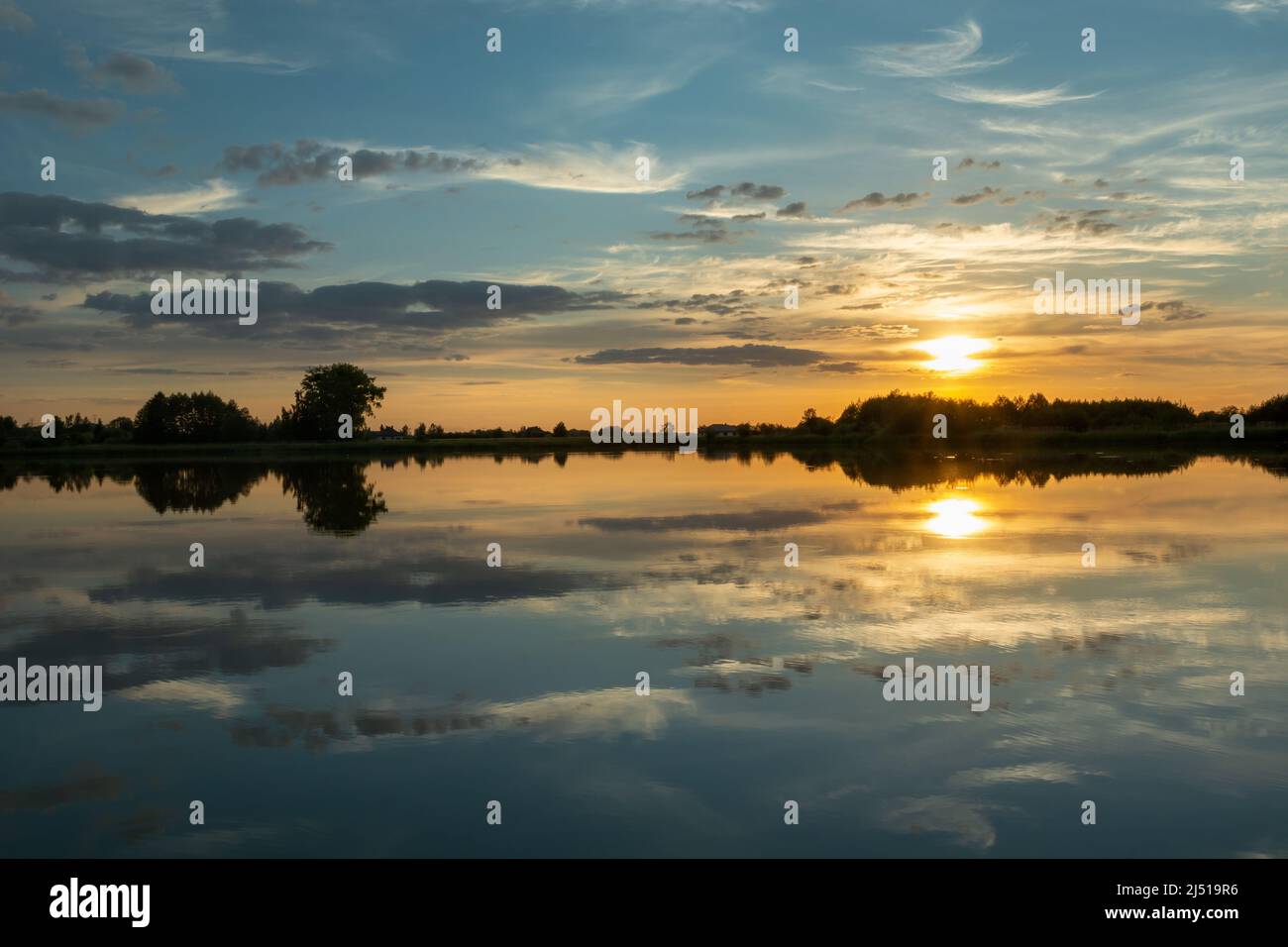 Spiegelung der Wolken im ruhigen Seenwasser während des Sonnenuntergangs Stockfoto