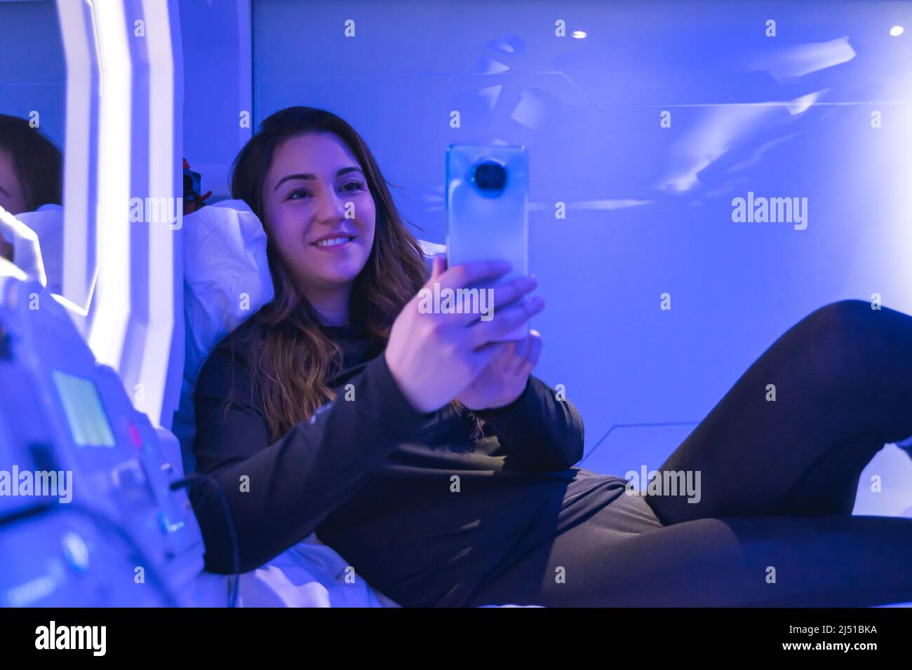 Frau in Kapsel in der Nacht mit dem Telefon Stockfoto