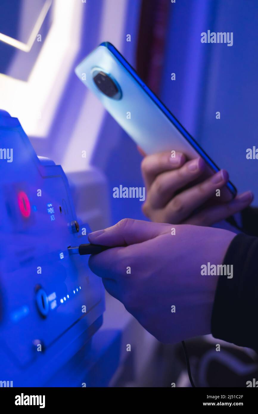 Frau lädt ihr Gerät in der Schlafkapsel auf. Stockfoto