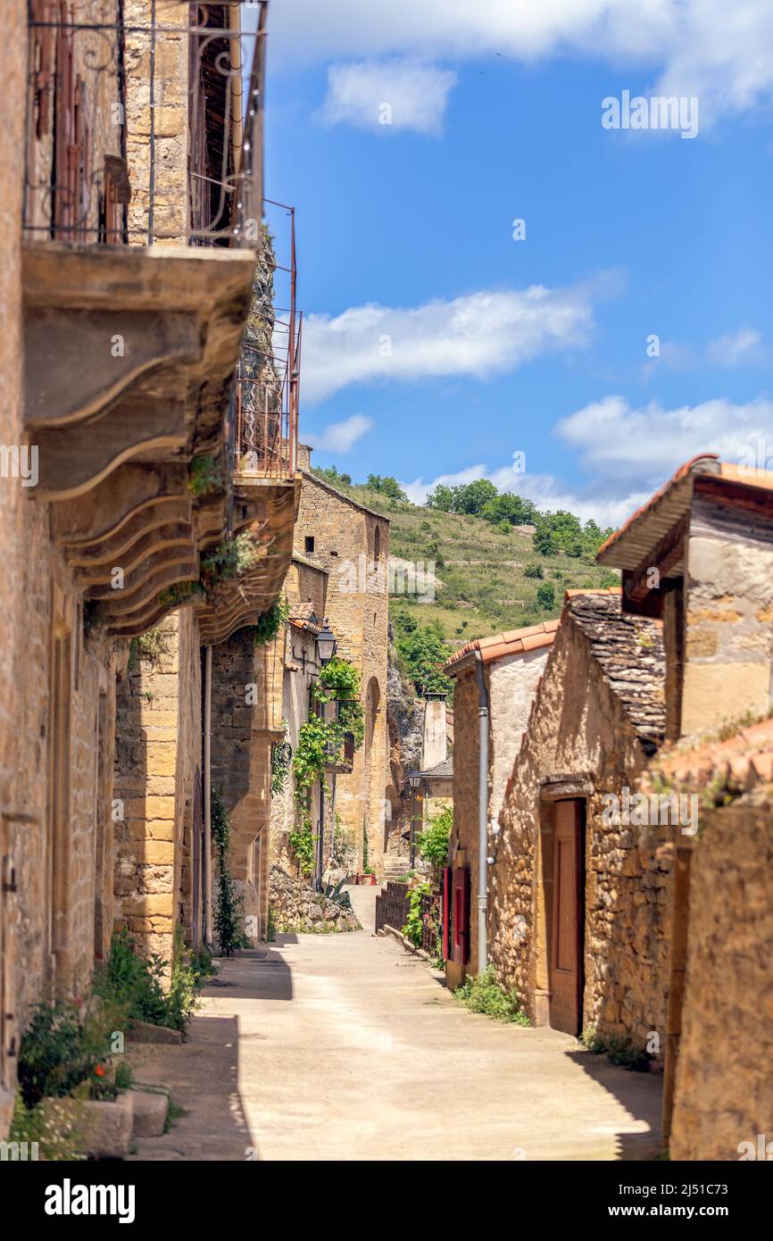 Enge helle Straßen des Dorfes Peyre mit Kalksteingebäuden verschiedener Epochen mit dekorierten Balkonen. Aveyron, Ozitanien, Südfrankreich Stockfoto