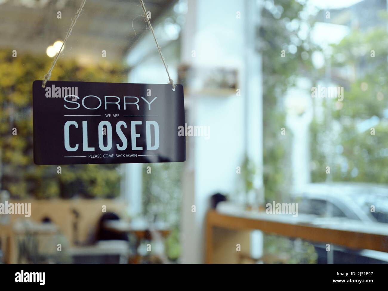 Das Schild des Business Coffee Cafe Shops hängt an der Tür und zeigt „Sorry, dass wir geschlossen sind“ mit einem Bokeh-Hintergrund im Café und Restaurant. Stockfoto