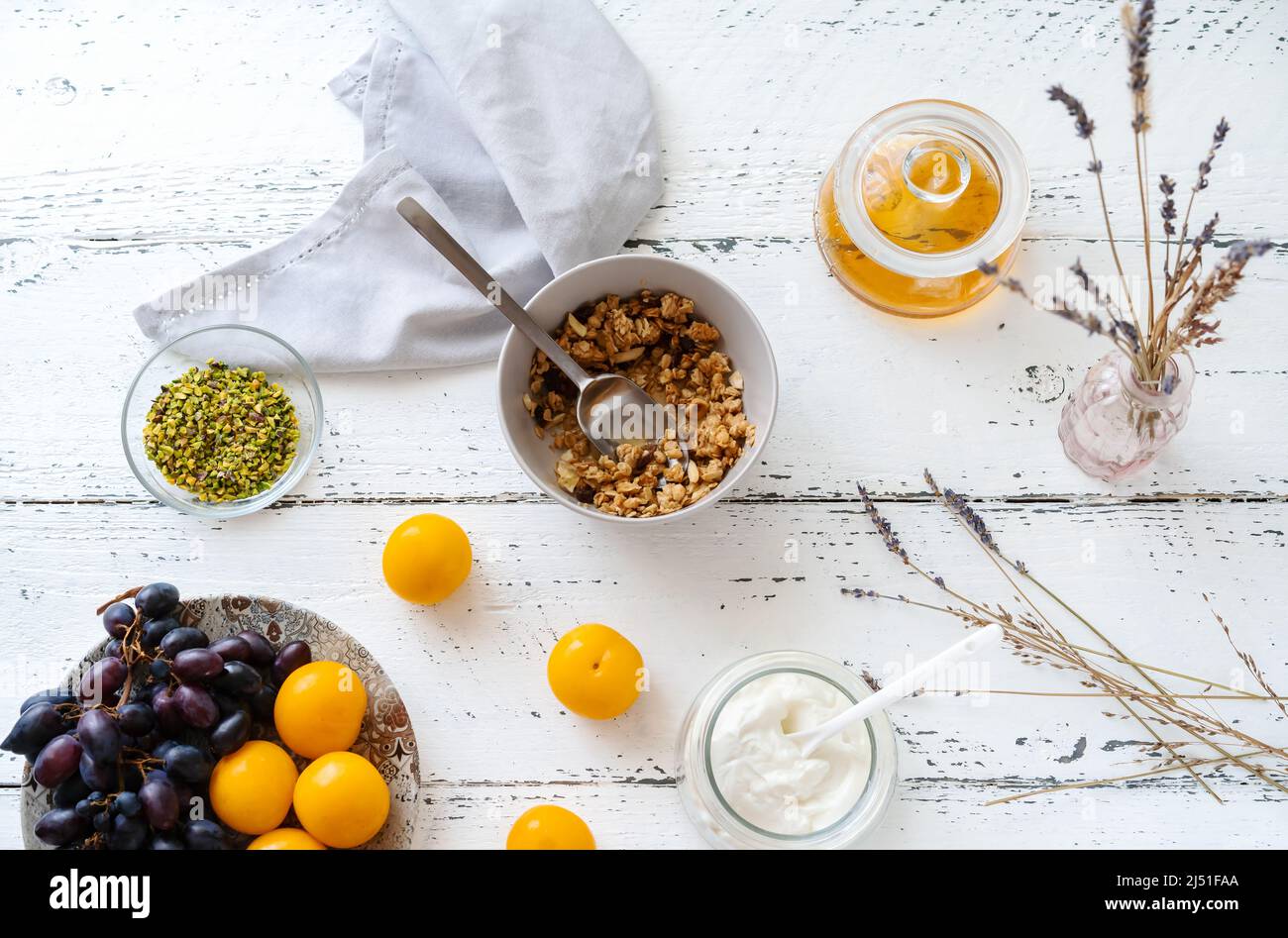 Frühstückskonzept mit Müsli, Honig, Joghurt und Obst Stockfoto