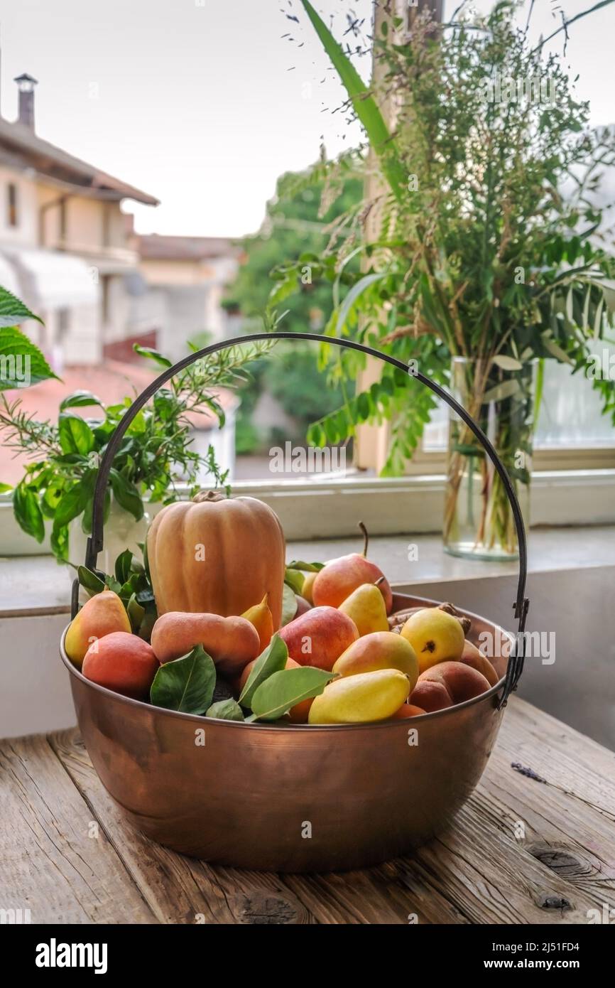 Obst und Gemüse in einer großen Kupferschüssel mit Blick auf das Land vom Fenster aus Stockfoto