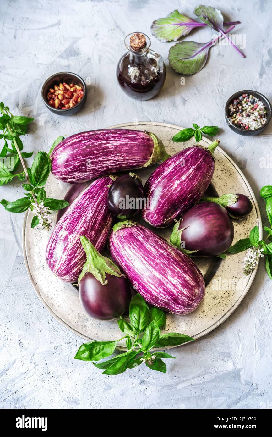 Auberginen auf dem Teller mit Kräutern, Olivenöl und Gewürzen Stockfoto